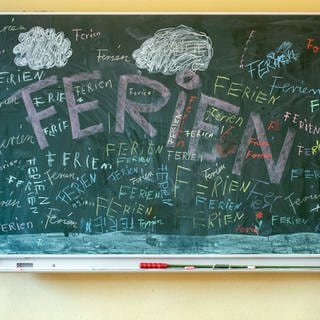 Das Wort "Ferien" steht an einer Tafel in einem Klassenzimmer einer Grundschule. 