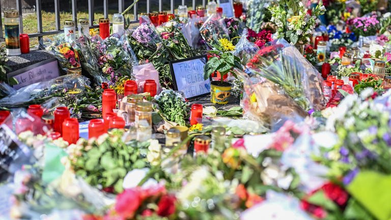Nach dem Tod eines Polizisten, der nach einer Messerattacke mit mehreren Verletzten gestorben ist, liegen am Marktplatz in der unmittelbaren Nähe des Tatorts Blumen und Kerzen.