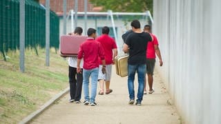 Männer gehen auf einem Weg zu einer Aufnahmeeinrichtung für Flüchtlinge.
