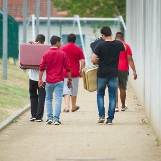 Männer gehen auf einem Weg zu einer Aufnahmeeinrichtung für Flüchtlinge.