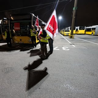 Teilnehmerinnen und Teilnehmer eines Warnstreiks stehen in einem Busdepot der Stuttgarter Straßenbahnen AG (SSB). 