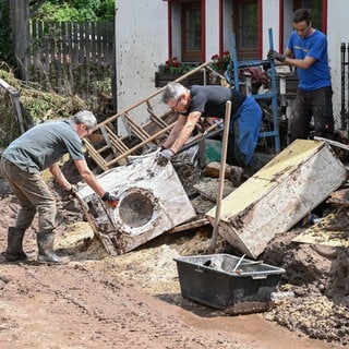 Helfer bergen in Klaffenbach bei Rudersberg (Rems-Murr-Kreis) Gegenstände, die durch ein Hochwasser nach einem Unwetter zerstört wurden.