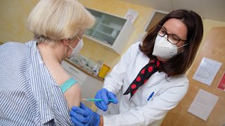 Nicola Buhlinger-Göpfarth (r), Fachärztin für Allgemeinmedizin, impft in ihrer Praxis eine Patientin gegen das Coronavirus.