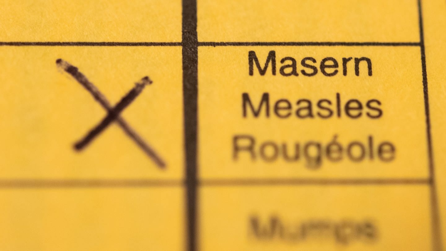 Ein Impfpass mit einem Kreuz bei der Masern-Impfung liegt auf einem Tisch.