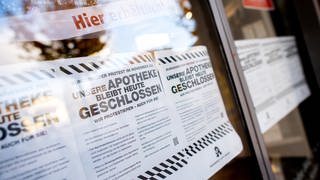 Ein Schild mit der Aufschrift "Unsere Apotheke bleibt heute geschlossen" hängt in der Eingangstür einer Apotheke.