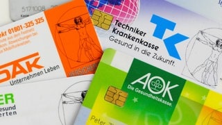 Krankenkassenkarten von gesetzlichen Krankenkassen liegen auf einem Tisch