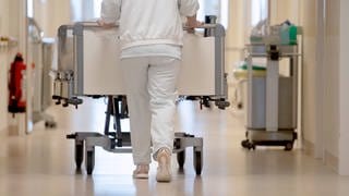 Eine Krankenpflegerin schiebt ein Krankenbett durch einen Flur