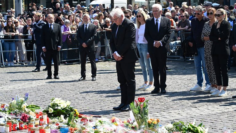 Bundespräsident Frank-Walter Steinmeier (vorn) legt bei einer Gedenkminute für einen bei einem Messerangriff getöteten Polizisten auf dem Marktplatz einen Trauerkranz nieder.