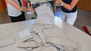Die Stimmzettel zur Europawahl werden aus einer Wahlurne ausgeschüttet. 