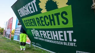 Zwei Mitarbeiter einer Firma für Werbeaufsteller bauen ein Wahlplakat der Partei Bündnis 90Die Grünen nach der Europawahl ab.