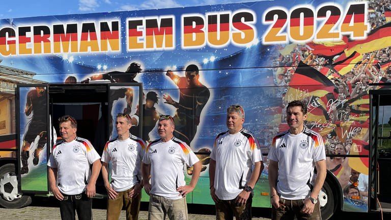 Vier Männer aus Ochsenhausen stehen vor ihrem selbst umgebauten EM-Bus. Damit wollen sie zu den Turnierstädten der EURO 2024 fahren.