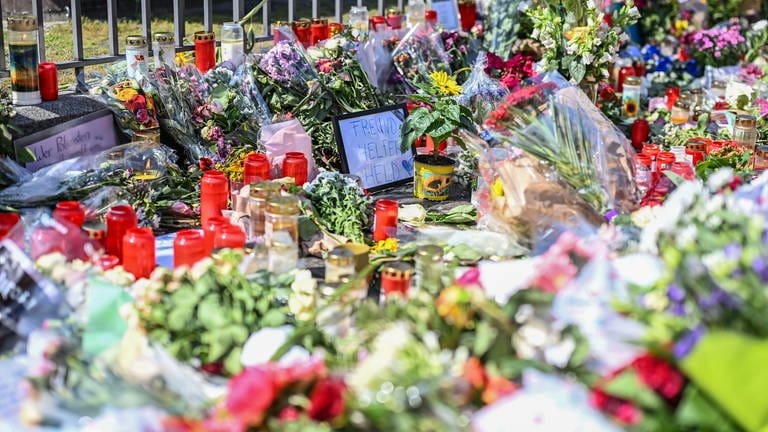 Nach dem Tod eines Polizisten, der nach einer Messerattacke mit mehreren Verletzten gestorben ist, liegen am Mannheimer Marktplatz in der unmittelbaren Nähe des Tatorts Blumen und Kerzen.