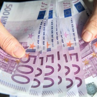 Eine Person hält mehrere 500-Euro-Scheine in den Händen.