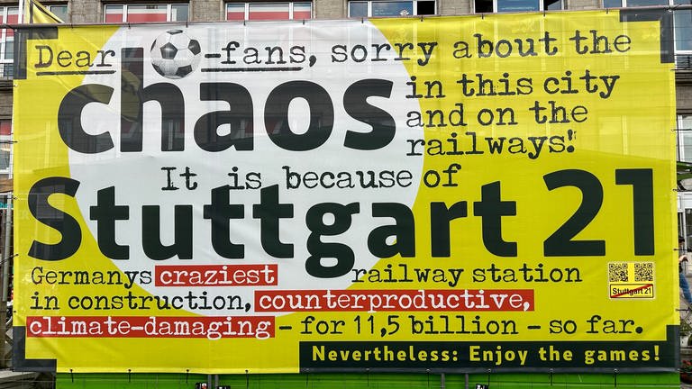 Gegner von Stuttgart 21 haben am Hauptbahnhof in Stuttgart ein Plakat aufgehängt. Zugespitzt erklären die Fußball-Fans auf Englisch ihre Kritik an S21.