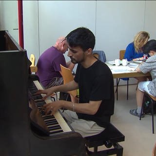 Der junge Afghane Zaki Darya spielt auf einem Klavier