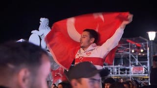 Ein Mann mit einer Türkei-Flagge feiert, dass die türkische Nationalmannschaft im Fußball ins EM-Viertelfinale eingezogen ist.