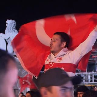 Ein Mann mit einer Türkei-Flagge feiert, dass die türkische Nationalmannschaft im Fußball ins EM-Viertelfinale eingezogen ist.