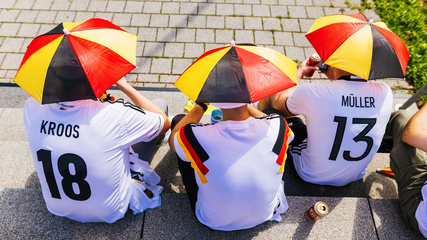 EM-Fußballfans sitzend mit Miniatur-Schirmen auf dem Kopf