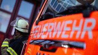 Eine Einsatzkraft steht neben einem Einsatzfahrzeug der Feuerwehr.