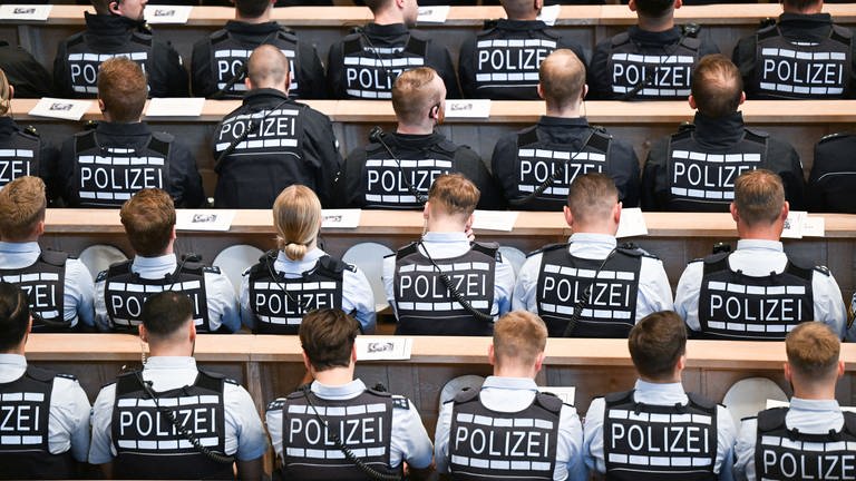 Polizistinnen und Polizisten sitzen in der Domkirche St. Eberhard in Stuttgart bei einem Trauergottesdienst.