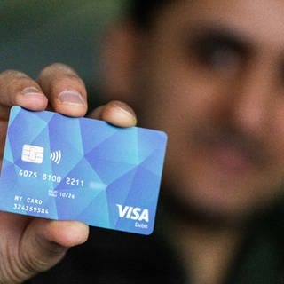 Ein Geflüchteter hält eine Debitcard in der Hand (Archivbild).
