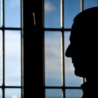 Ein Gefängnisinsasse sitzt in der Justizvollzugsanstalt in Heilbronn (Baden-Württemberg) vor einem vergitterten Fenster.