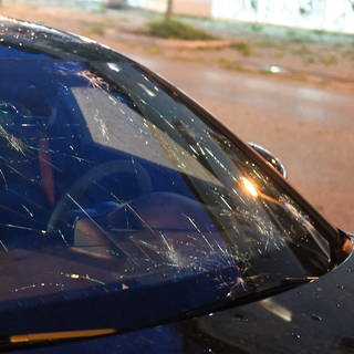 Eine von Hageleinschlägen getroffene Windschutzscheibe eines Autos.