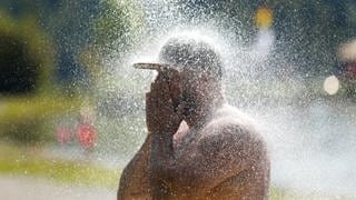 Ein Mann erfrischt sich an einem Badesee unter einer kalten Dusche. Es waren Temperaturen über 30 Grad Celsius vorhergesagt.
