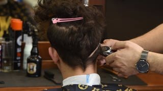 In einem Barbershop werden einem Kunden die Haare geschnitten.