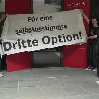 Zwei Personen halten einen Banner mit der Aufschrift "Für eine selbstbestimmte dritte Option!" Dabei geht es um das neue Selbstbestimmungsrecht.