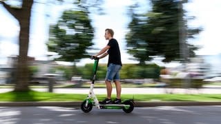 Ein Mann fährt in Stuttgart auf einem E-Scooter.