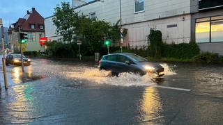 Ein Auto fährt in Kirchtellinsfurt über eine überschwemmte Straße.