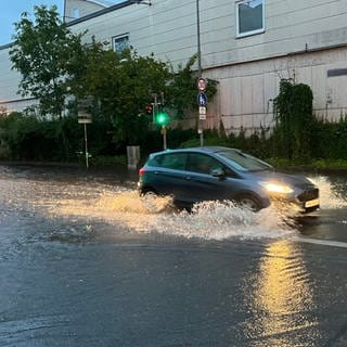 Ein Auto fährt in Kirchtellinsfurt über eine überschwemmte Straße.