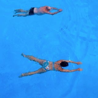 Zwei Badegäste schwimmen am 2. August 2024 im Freibad von Zwiefalten (Kreis Reutlingen).