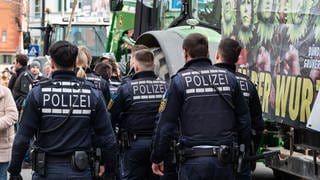 Polizisten gehen während einer Demonstration vor Beginn des politischen Aschermittwochs der baden-württembergischen Grünen vor der Stadthalle in Biberach an der Riß.