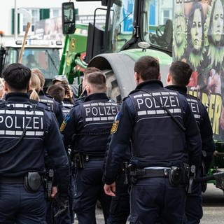 Polizisten gehen während einer Demonstration vor Beginn des politischen Aschermittwochs der baden-württembergischen Grünen vor der Stadthalle in Biberach an der Riß.