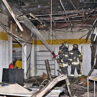 Zwei Feuerwehrmänner stehen in einem abgebrannten Gebäude in Gerlingen