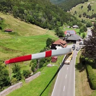 Das Rotorblatt eines Windrads wird von einem Schwertransporter auf einer Landsstraße transportiert