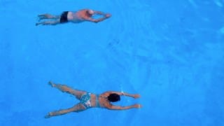 Badegäste schwimmen in Freibad von Zwiefalten im Wasser.