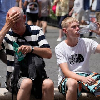 Symbolbild: Touristen erfrischen sich mit Wasser bei Hitze.