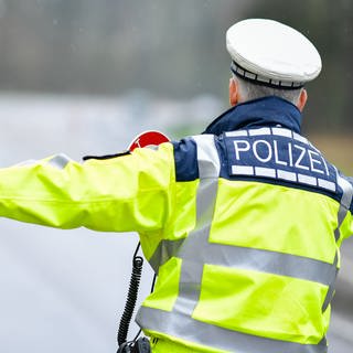 Ein Polizist hält bei einer Geschwindigkeitskontrolle ein Fahrzeug an.