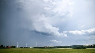 Eine Regenfront mit dunklen Wolken ist hinter einem Gerstenfeld bei Böhmenkirch zu sehen. 