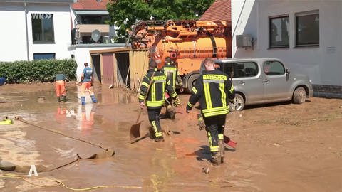 Arbeiter beim Aufräumen in einer überschwemmten Straße