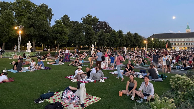 Viele Besucher der Schlosslichtspiele Karlsruhe machen es sich auf dem Rasen auf Decken gemütlich, um sich die Illuminationen anzuschauen. 