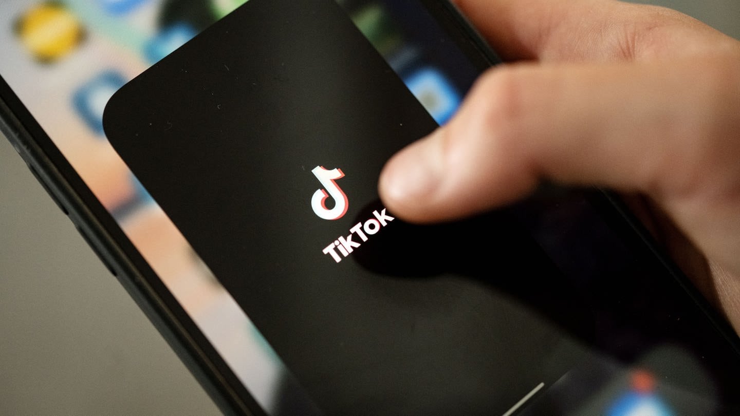 Ein Teenager tippt auf das TikTok-Logo auf einem Smartphone (Symbolbild).