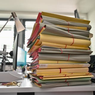 Ein Stapel mit Akten liegt auf einem Schreibtisch in einem Behördenbüro