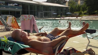 ein Mann sonnt sich auf einer Liege in einem Freibad