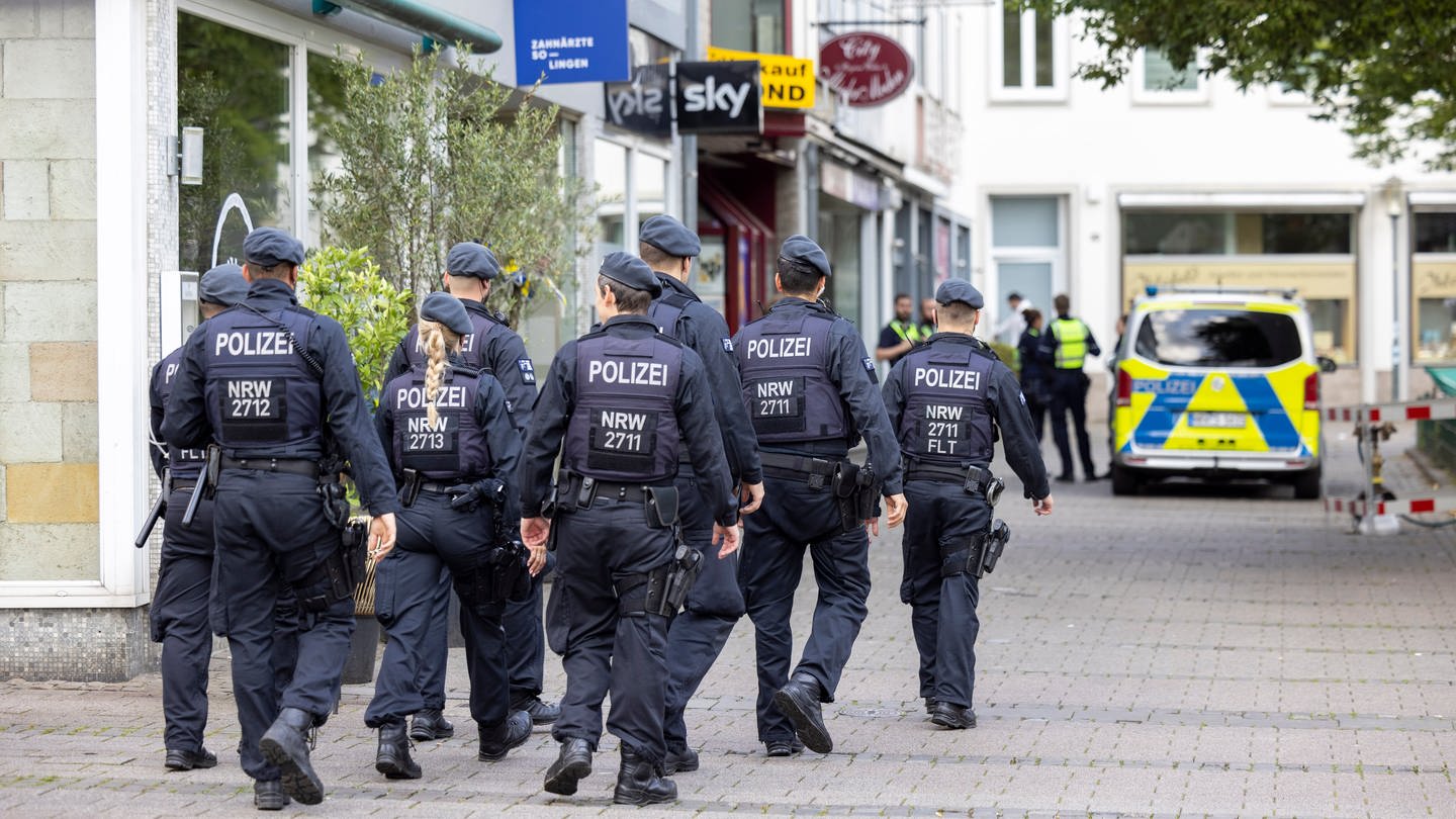 Einsatzkräfte der Polizei gehen am Mittag am Tatort vorbei. Bei einer Attacke auf der 650-Jahr-Feier der Stadt Solingen am 23.08.2024 hat es drei Todesopfer und mehrere Verletzte gegeben.