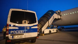 Ein Polizist steht auf diesem Archivbild vom Juli 2019 neben einem Transporter, der Menschen am Flughafen Leipzig zu einem Abschiebeflugzeug nach Afghanistan gebracht hat. 