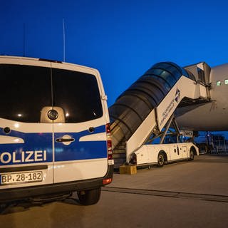 Ein Polizist steht auf diesem Archivbild vom Juli 2019 neben einem Transporter, der Menschen am Flughafen Leipzig zu einem Abschiebeflugzeug nach Afghanistan gebracht hat. 